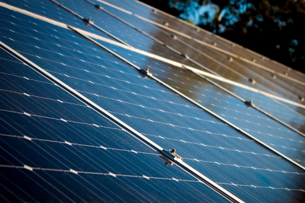 A view of solar panels with the sunlight reflecting off them.