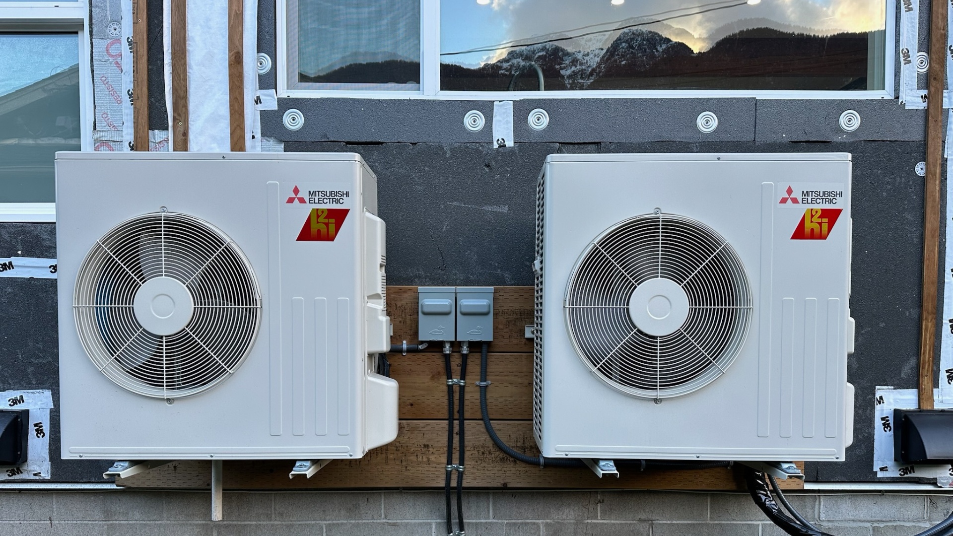 Two Mitsubishi heat pumps installed on the exterior of a house.